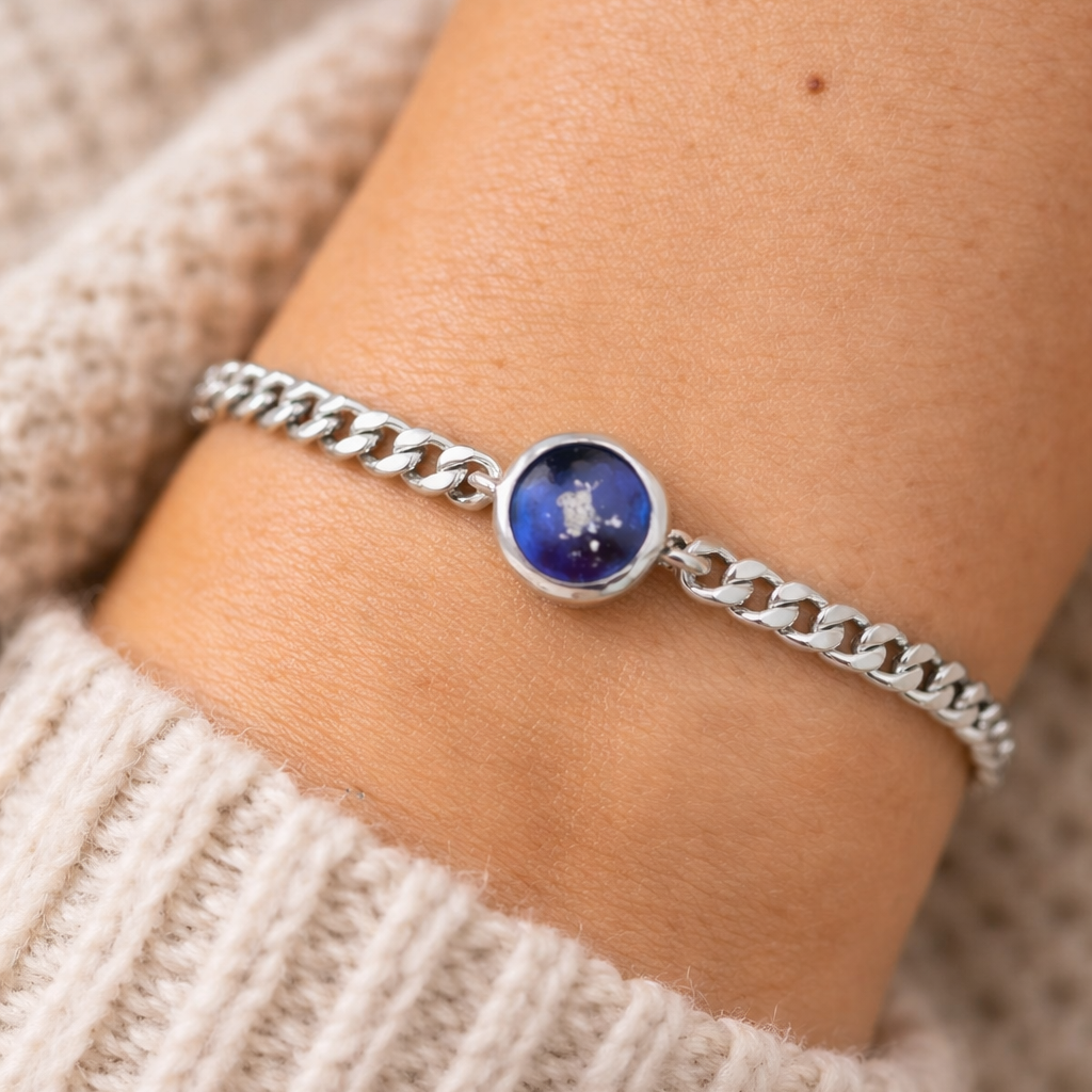 Silver bracelet with a blue gemstone on a wrist, wearing a beige sweater.